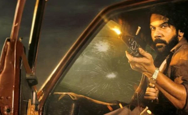A man with a gun inside a car with bullet - riddled glass in the movie "Maalik".