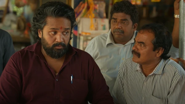 Men engaged in conversation in "Su from So".