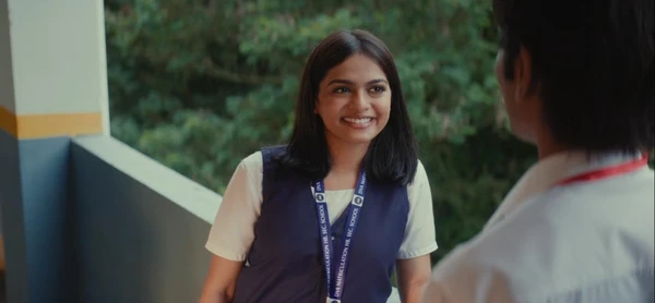 A girl smiles brightly at someone in a school corridor in Dragon.