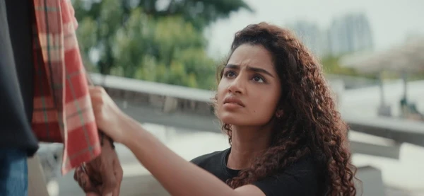 A woman with curly hair holds someone's hand, looking concerned in Dragon.