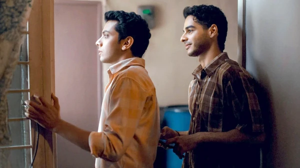 Two men stand by a window in a room in Homebound.